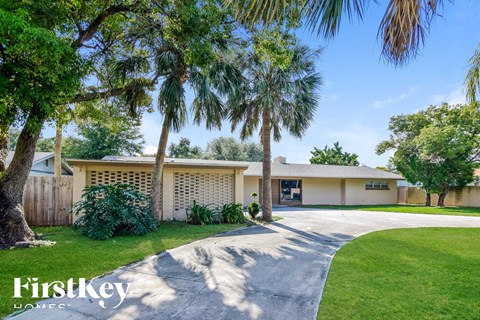a house with palm trees in front of it and a driveway