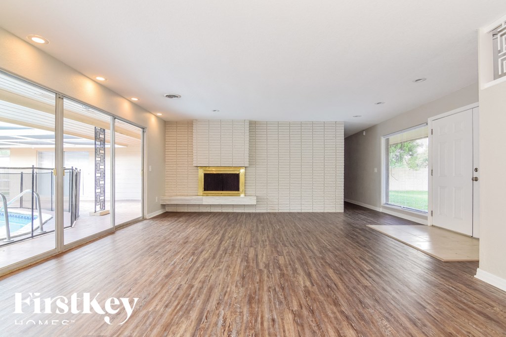 an empty living room with a fireplace and wooden floors