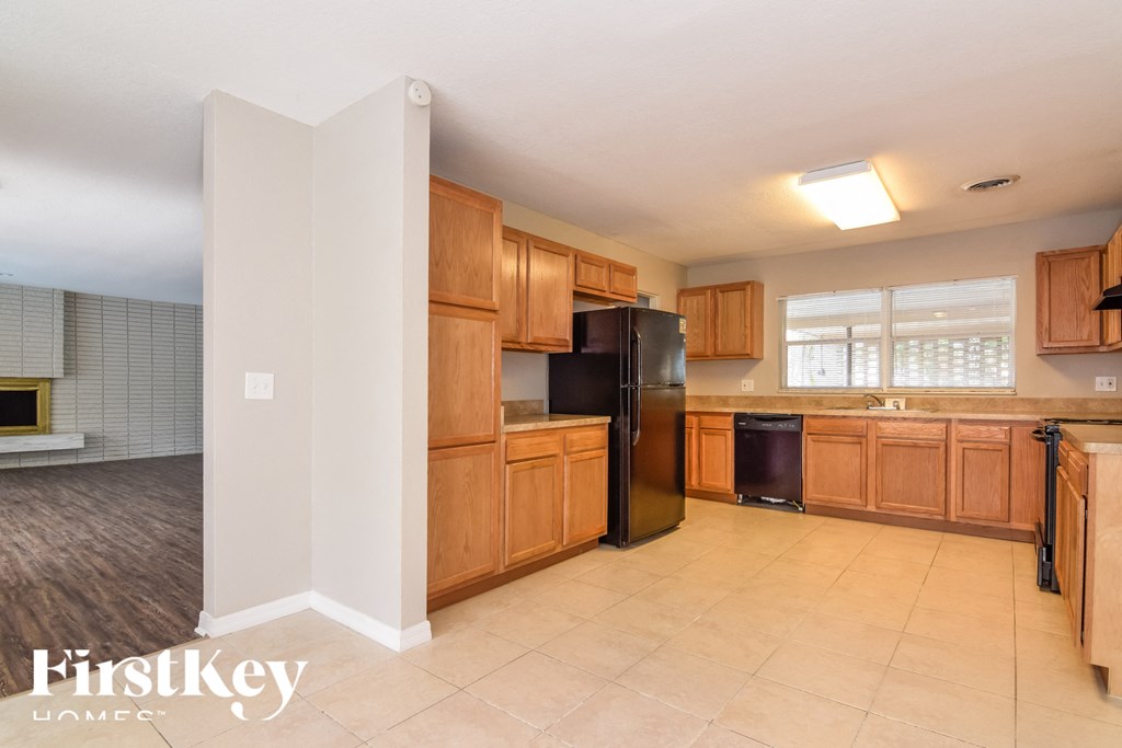 a kitchen with wooden cabinets and a black refrigerator
