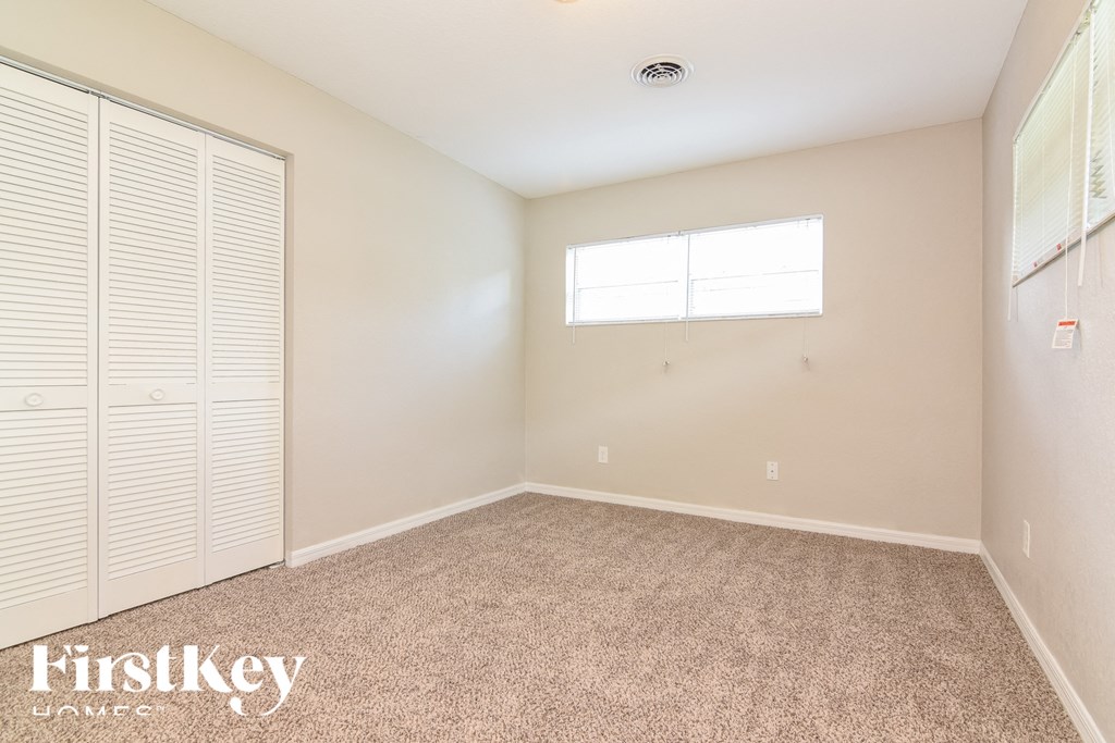 a bedroom with carpet and a closet and a window