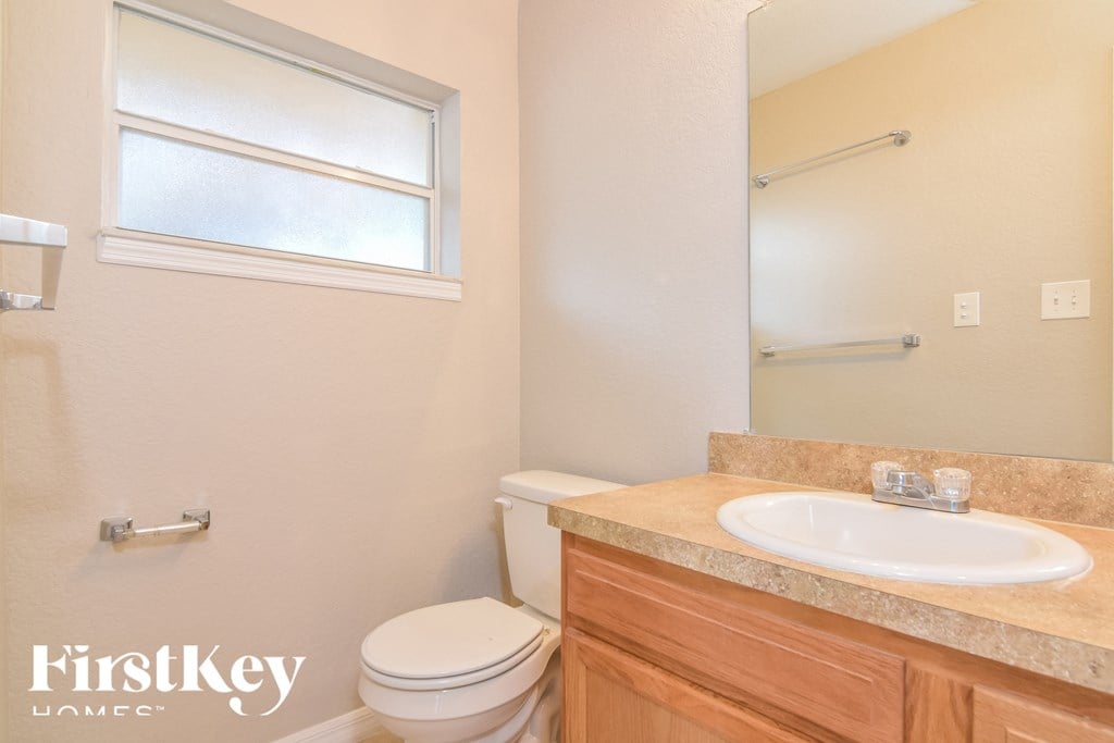 a bathroom with a toilet and a sink and a window