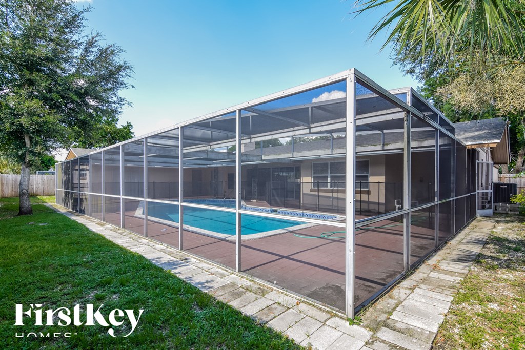 a glass enclosure with a pool in a backyard