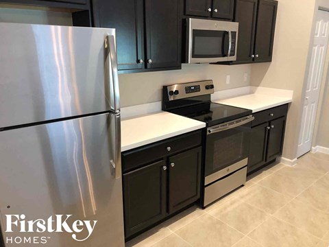 A kitchen with a refrigerator, microwave, oven and cabinets.