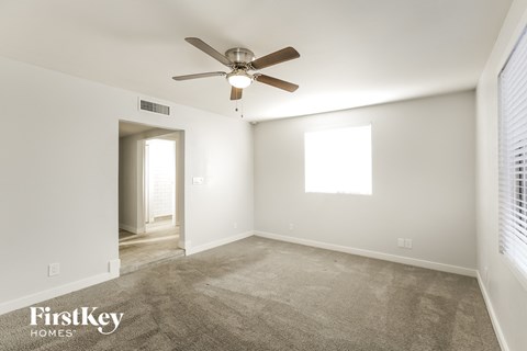 a living room with carpet and a ceiling fan