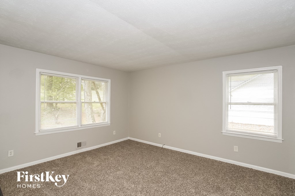 a bedroom with a carpeted floor and two windows