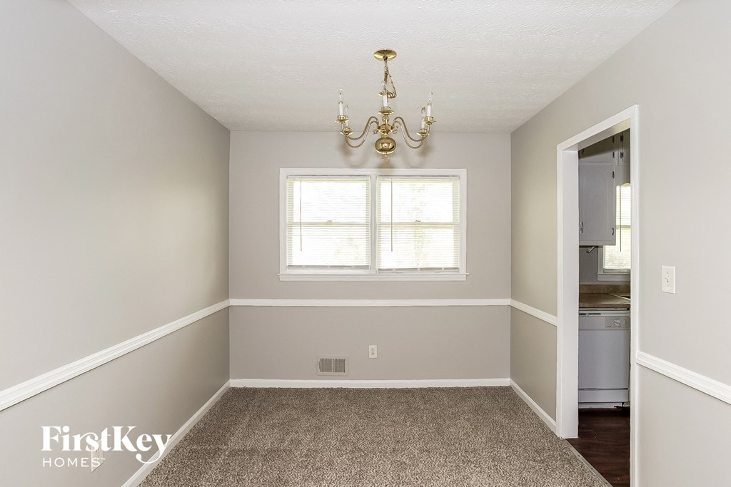 a empty dining room with a chandelier and a window