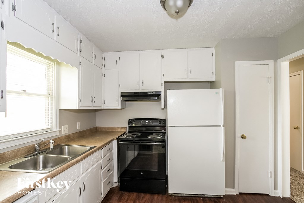 a white kitchen with black appliances and white cabinets