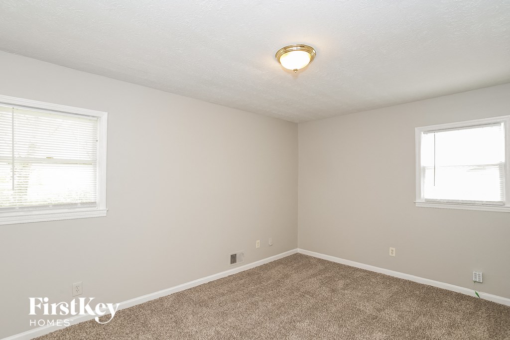 a bedroom with a carpeted floor and two windows