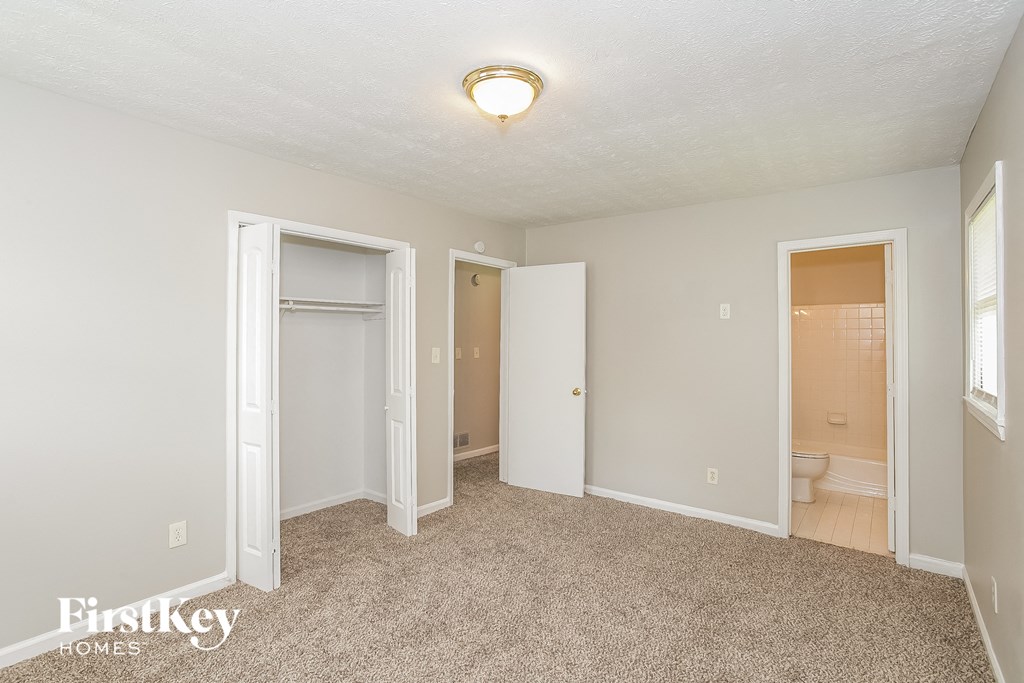 a bedroom with a carpeted floor and a door to a bathroom