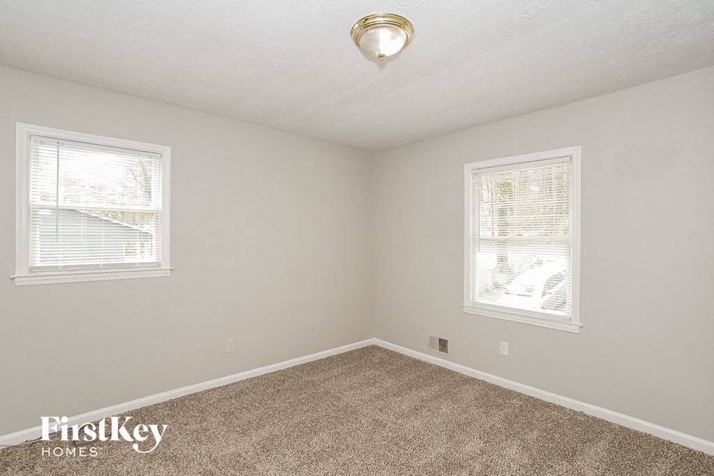 a bedroom with two windows and a carpeted floor