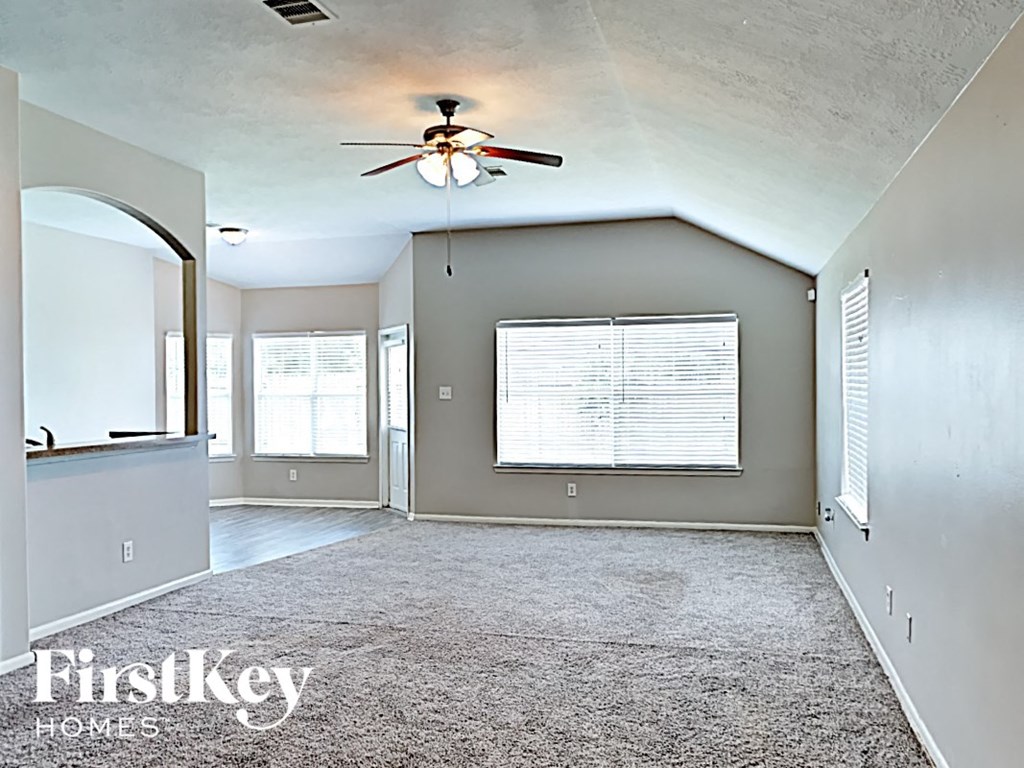 an empty living room with a ceiling fan and a window