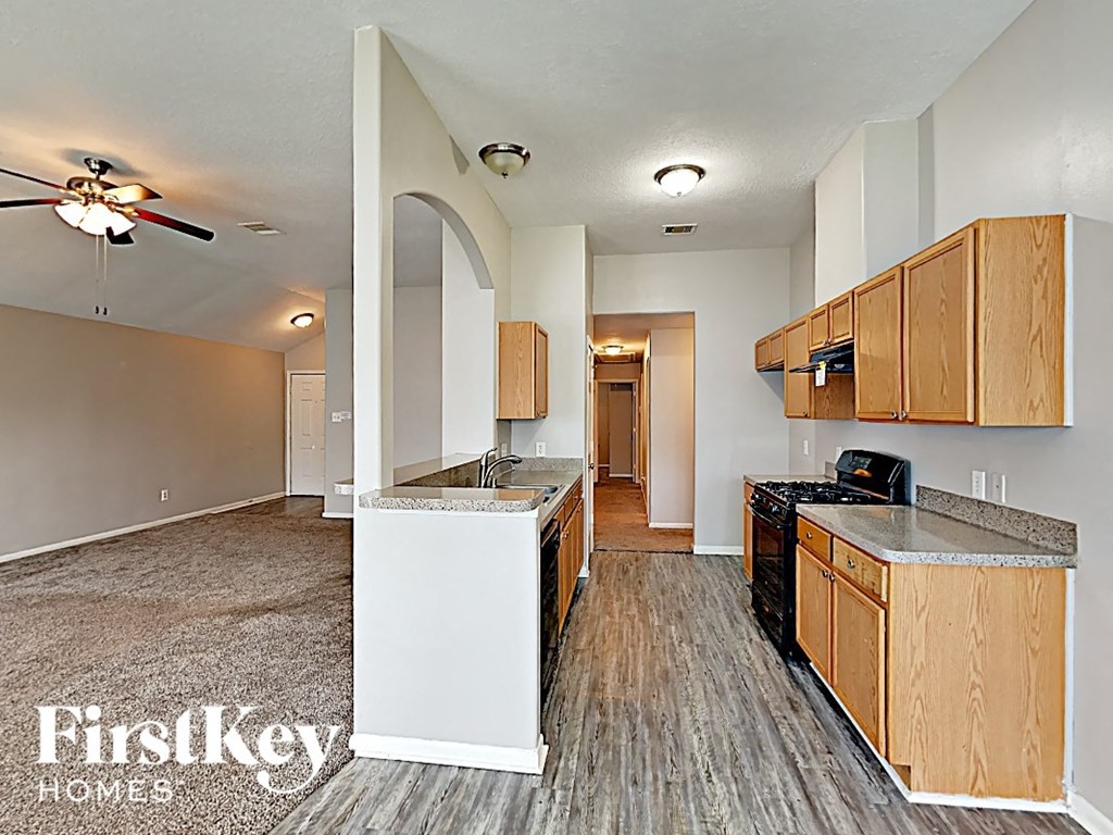an empty kitchen with wood flooring and a ceiling fan