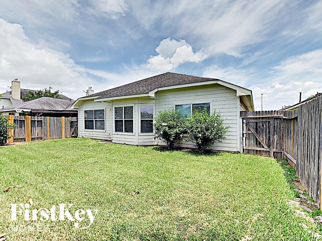 a small white house with a yard and a fence