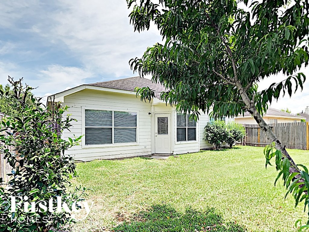 a small white house with a yard and a tree