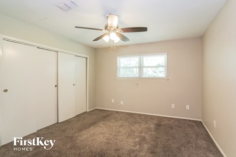 a bedroom with carpet and a ceiling fan and a closet