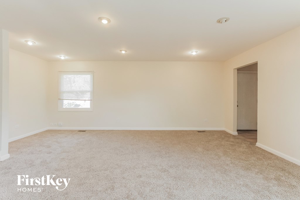 A spacious room with a carpeted floor and a window letting in natural light.