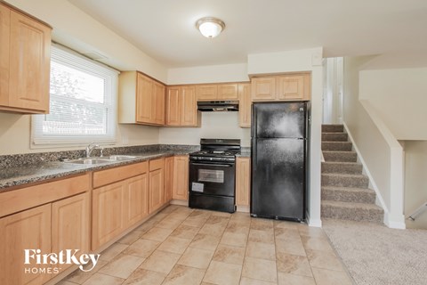 A kitchen with wooden cabinets and a black fridge.