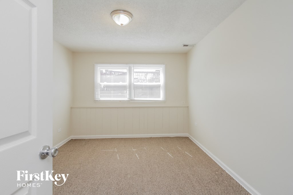A carpeted room with a window and a door.