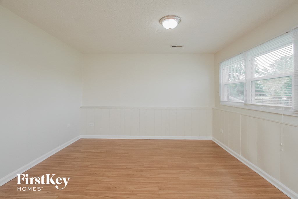 A room with wooden flooring and a window with blinds.