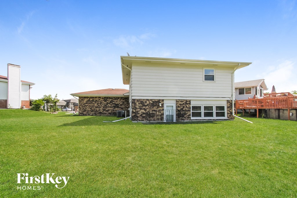 A house with a stone wall and a white siding is for sale.