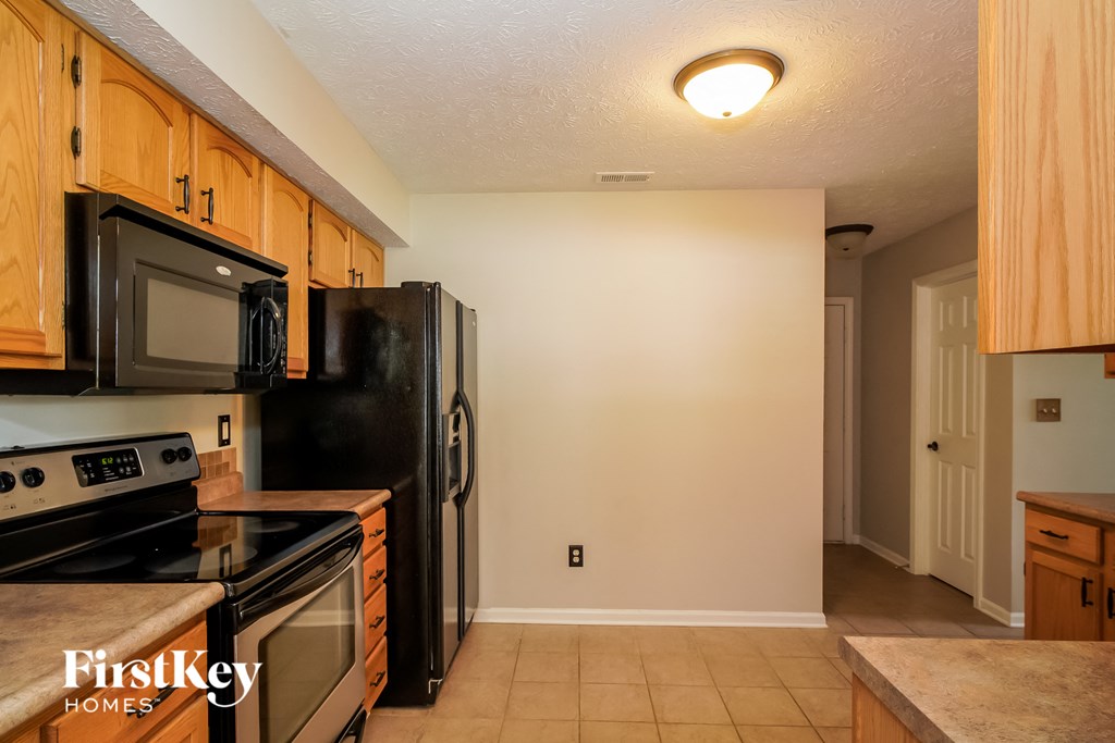 full view of the kitchen with black appliances and wood cabinets
