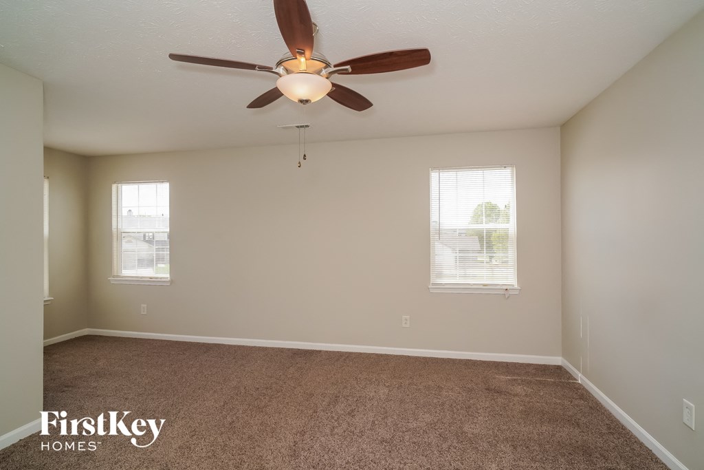 a empty room with a ceiling fan and two windows