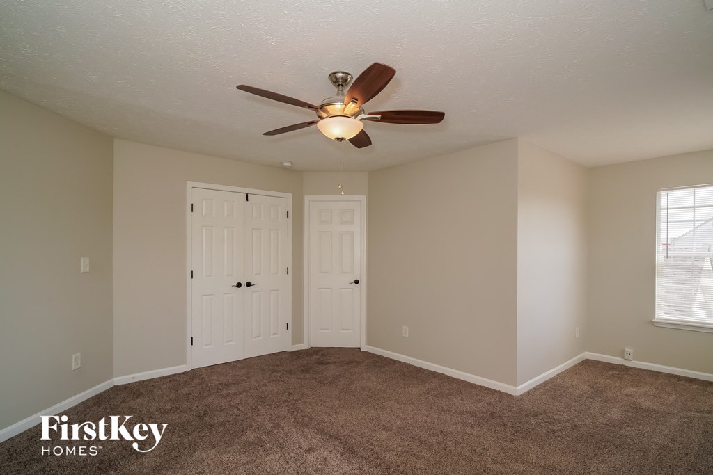 a living room with carpet and a ceiling fan