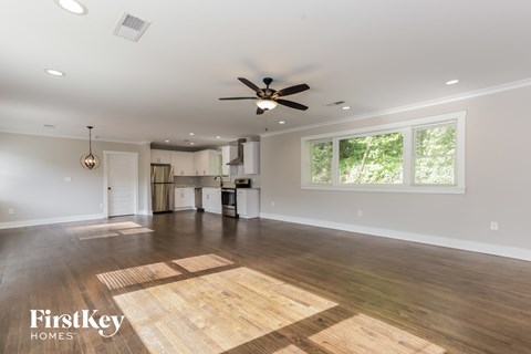 A spacious room with wooden flooring and a ceiling fan.