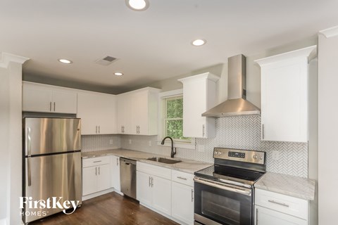 A kitchen with white cabinets and a stainless steel refrigerator.