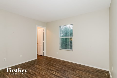 A room with a door and a window with a view of trees.