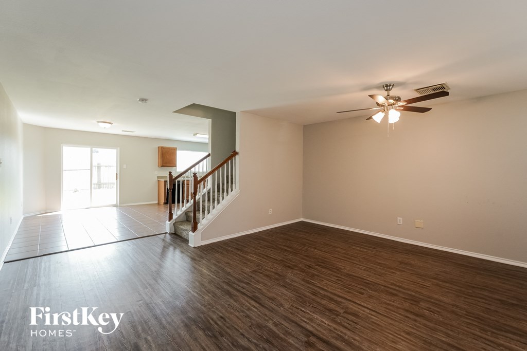 an empty living room with wood flooring and a ceiling fan