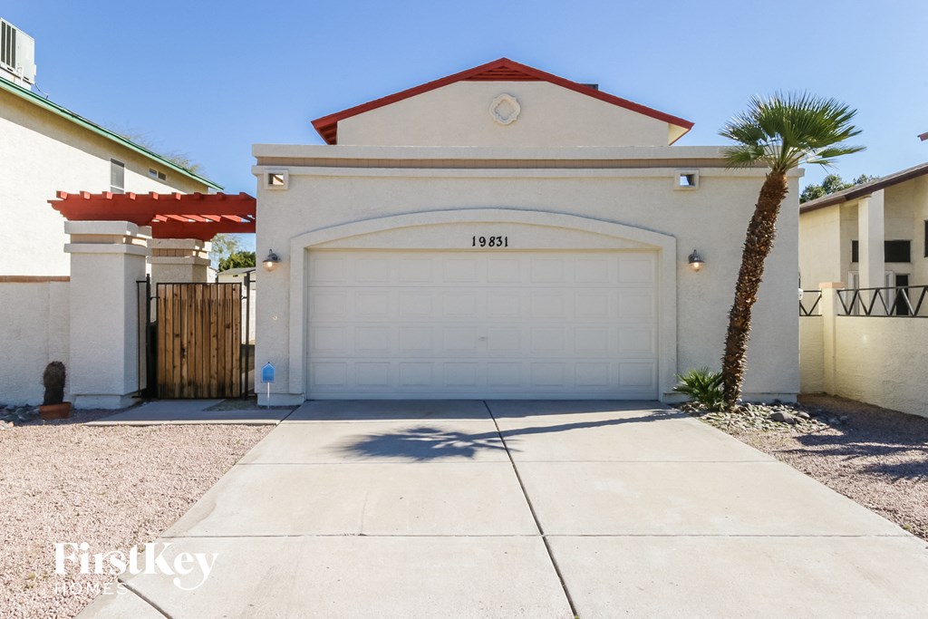 a white house with a white garage door and a palm tree