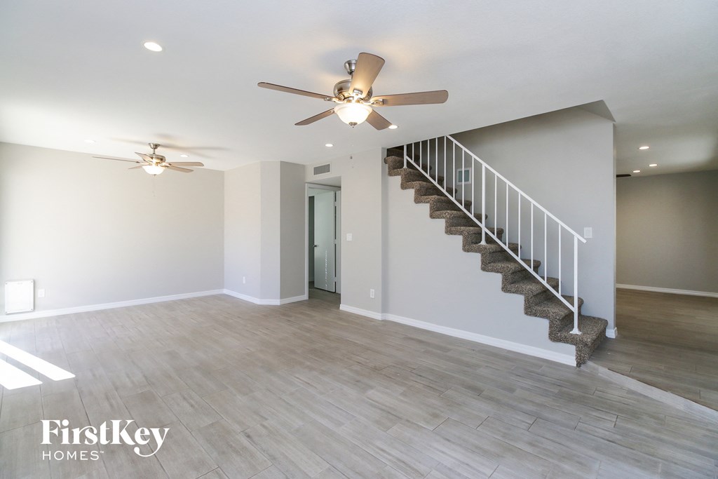 a living room with a staircase and a ceiling fan