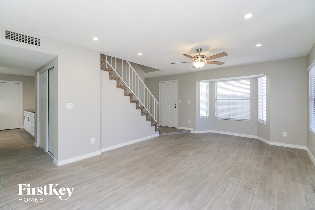 an empty living room with a staircase and a ceiling fan