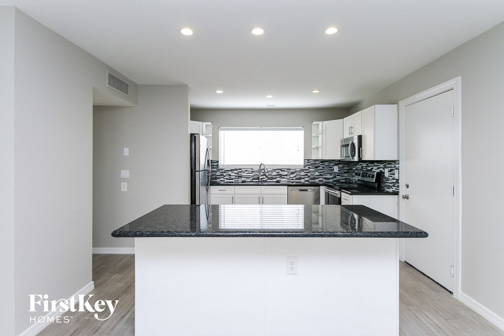 a kitchen with white cabinets and a black counter top