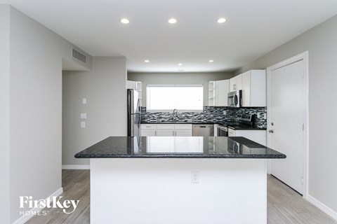 a kitchen with white cabinets and a black counter top