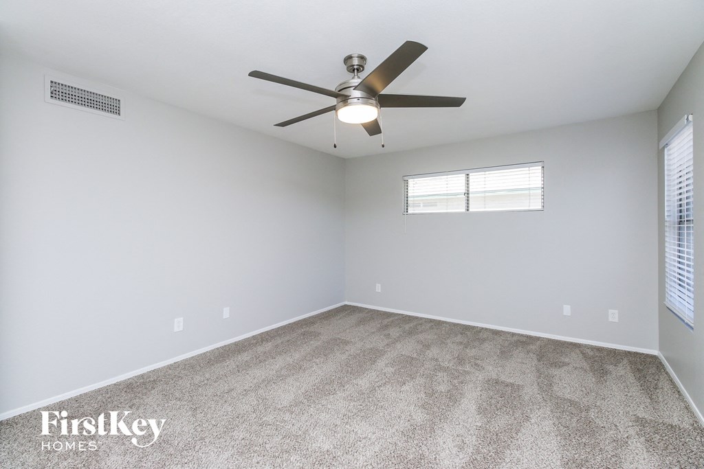 an empty room with a ceiling fan and a window
