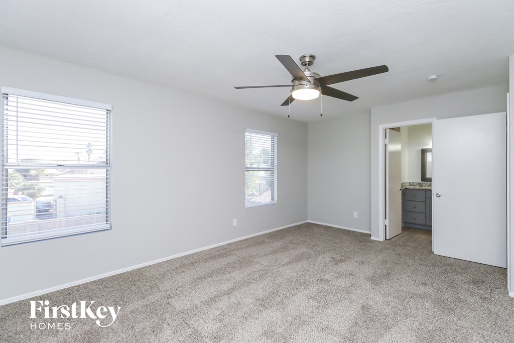 an empty living room with a ceiling fan and a window