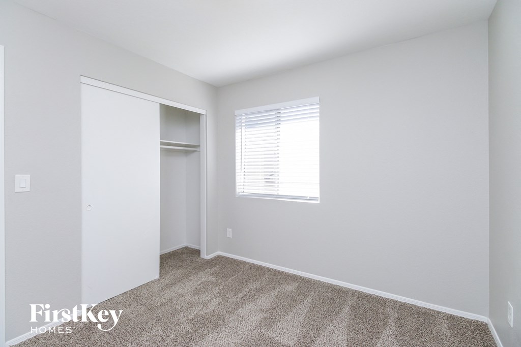 a bedroom with white walls and a closet and a window