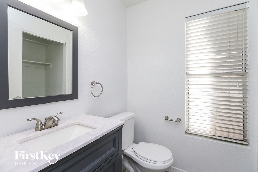a white bathroom with a white toilet and a sink and a mirror