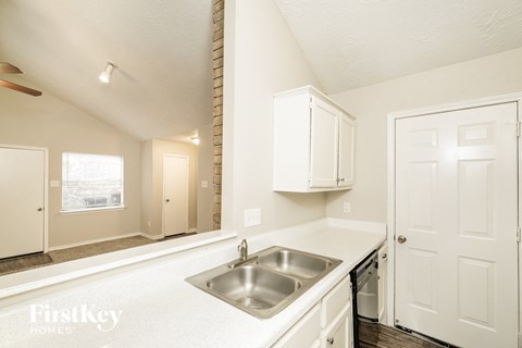 a kitchen with white cabinets and a sink and a window