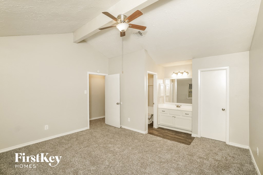 a bedroom with a ceiling fan and a bathroom