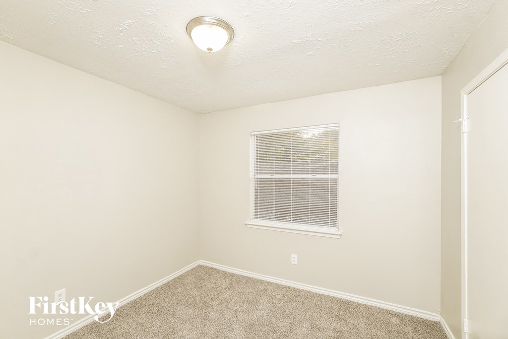 a bedroom with a window and a carpeted floor