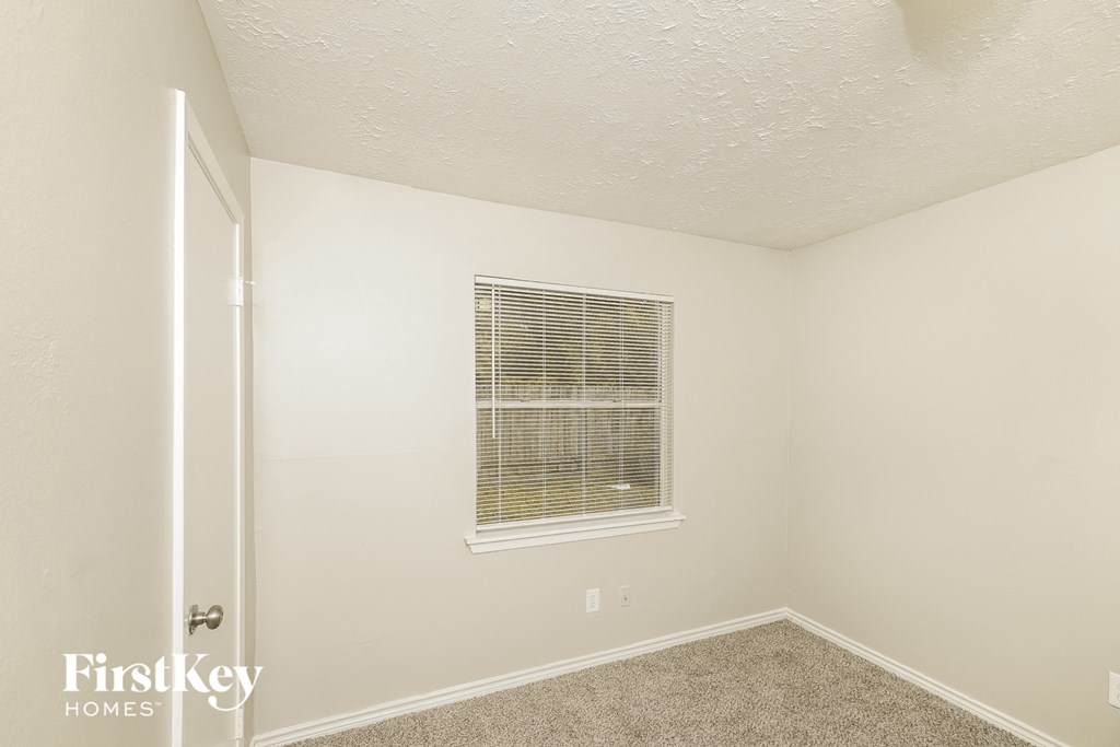 a bedroom with white walls and carpet and a window