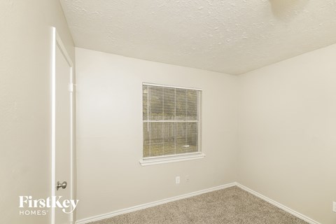 a bedroom with white walls and carpet and a window