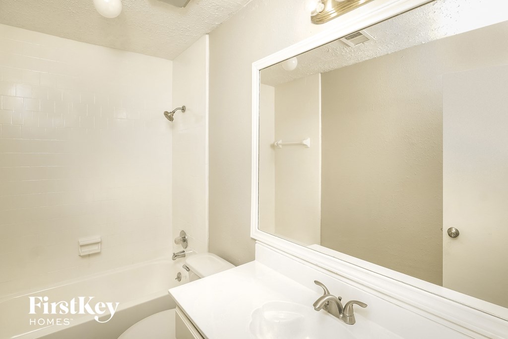 a white bathroom with a large mirror and a white tub and sink