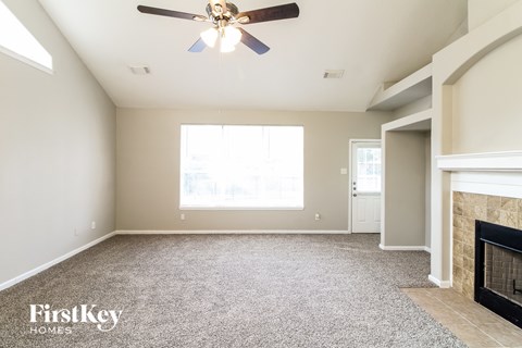 an empty living room with a ceiling fan and a fireplace