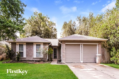a small brick house with a driveway and a garage door