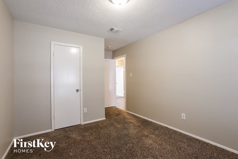 a bedroom with a carpeted floor and a door to a closet