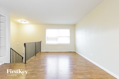 an empty living room with wood floors and white walls and a window
